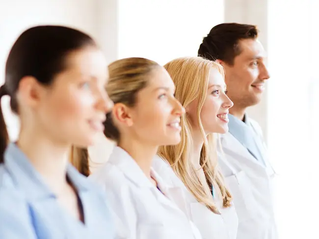 Vier Personen in weißer und blauer Arbeitskleidung stehen nebeneinander in einer Hautarztpraxis.