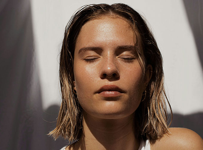 Eine Frau mit geschlossenen Augen und zurückgebundenem Haar.