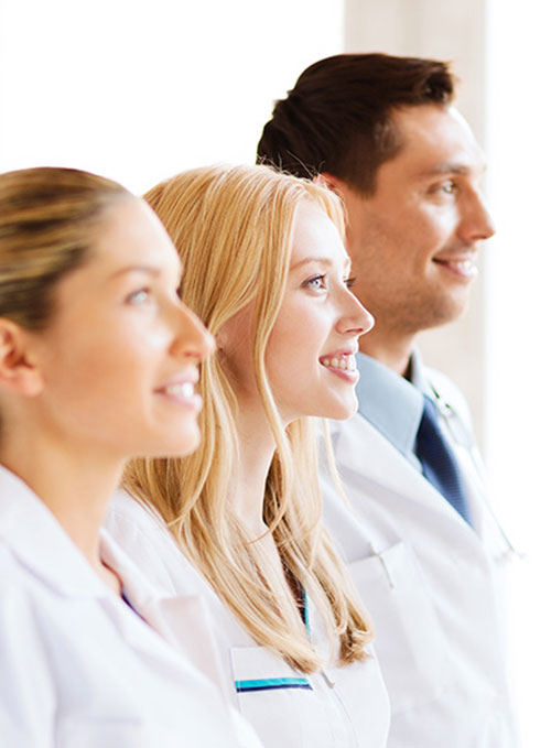 Vier Personen in weißer und blauer Arbeitskleidung stehen nebeneinander in einer Hautarztpraxis.